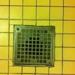 Right Past Down the Drain © 2012 NATE METZ - digital photograph of yellow tile and floor drain in a bathroom